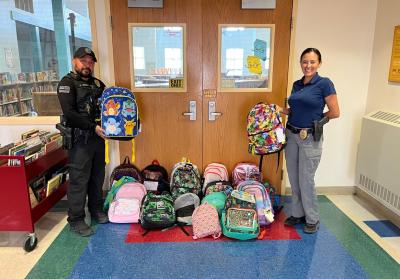 Corrales Police officers with backpack donations for kids